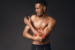 Handsome shirtless black man suffering from pain in hand
